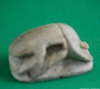 Side view of the miniature stone scarab showing carved legs and wings