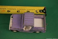 Purple die-cast toy pickup truck shown from top angle with measuring tape indicating about 3 inches long.