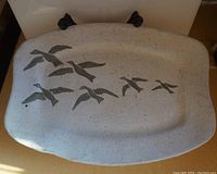 Top view of ceramic platter showing front side with hand-painted flying birds design
