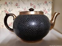 Front-side view of blue patterned Gibsons tea pot with gold-tone handle, rim and spout.