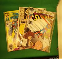 Photo showing three comic books in plastic protective sleeves: The Adventures of Superboy, Ghost Rider, and The Transformers comics.