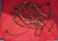 Eight metal vintage lamp harps piled together on a red cloth background, showing variety of sizes and shapes