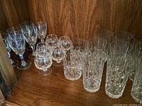 Wide view showing overall lot arrangement of 22 crystal glasses in varying types, all with similar cut patterns and no chips.