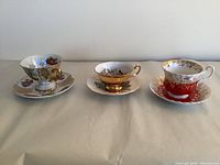Three fine English bone china tea cups and saucers displayed side by side showing variety of styles and colors