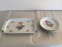 Full view of 7 piece set: 1 rectangular platter and 6 plates with floral decoration on white base and gold rims