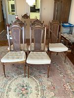 Front view of six chairs arranged in two rows on rug with kitchen in background