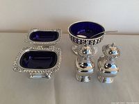 Front view of all six items showing silver detailing and blue glass inserts.