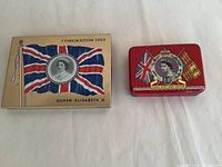 Two vintage cigarette tins commemorating Queen Elizabeth II, showing full front designs.