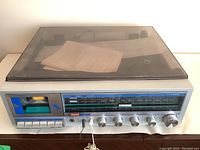 Front view showing cassette deck, control knobs and tuning dial under tinted cover