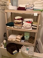 Shelf filled with various folded bathroom towels, safety pads, bath rug, cleaning supplies, and foot cleaner.
