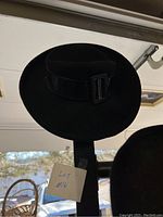 Black wide-brim hat with buckle, shown hanging