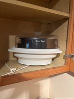 Hamilton Beach Rice Bowl steamer with transparent lid and white base inside wooden cabinet
