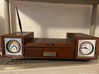 Photo showing mid-century modern radio with wood grain finish, two analog dials, and central drawer.
