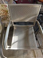 Close-up photo of a silver metal patio chair with square perforations on seat and back showing condition and design