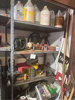 Metal shelving with assorted chemical containers, garden tools, and rope.