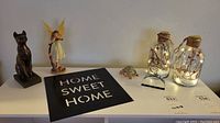Full lot overview showing all items arranged on a white surface including two jar lights, wall decor plaque, Sphinx figure, fairy, paperweight, and trinket box