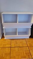 Front view of white cubby shelving unit showing 4 open compartments arranged in two rows.