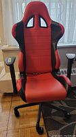 Front view of the red and black gaming chair showing the padded seat, headrest, and the overall racing-style design.