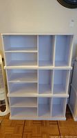 Front view of white KidsKraft storage cabinet showing cubby shelves arranged in two tiers with various sizes of compartments.