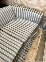 Close-up image of the left side of the couch showing the blue and cream striped upholstery and seat cushion.