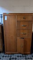 Front view of the Art Deco style armoire showing three drawers and two cupboards, with one knob missing and wood finish visible.