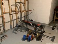 Overall view of Weider bench press setup with bars and weights on basement floor