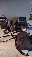 Lot overview of 4 cameras with cases and straps on table showing Minolta and Kodak brands.