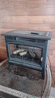 Front view of the Duraflame electric fireplace unit with remote on top