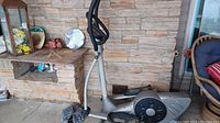 Side view of elliptical machine showing overall structure, pedals, and main body.