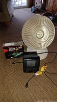 Photo of three items: Presto Heat Dish heater, Honeywell micro furnace heater, and boxed Electric Putting Partner golf trainer on carpeted floor.