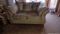 Front view of beige loveseat sofa showing two seat cushions and attached back cushions.