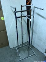 Photo showing front angle view of the chrome 4-arm clothing rack with adjustable height mechanism and rectangular base.