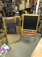 Side-by-side photo of the wood-framed mirror and children's easel with chalkboard in storage area.