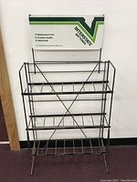 Full view of the black metal wire display rack with three shelves and Interstate Batteries sign on top.