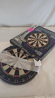 Tournament dartboard partially out of original box with visible numbering and color segments.
