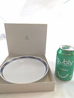 Furstenberg porcelain bowl with blue patterned rim inside original box, beside a soda can for size reference.