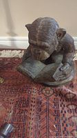 Front and side views of the metal monkey statue reading a book, showing detailed textured fur and open book.