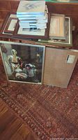 Overall view of stack of various sized picture frames on carpeted floor, large frame with Star Wars characters visible, another frame backside showing.