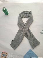 Full view of gray scarf laid flat with a drink can for scale, showing crystal embellishments.
