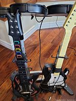 Close-up of two guitar controllers with cables and colored fret buttons visible.