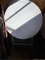 Four round plastic event tables stacked against a wall.
