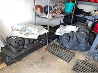 Black ballast bags piled beneath metal shelving alongside folded canvas and miscellaneous items