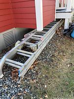 Folded 40-foot extension ladder laid on gravel showing aluminum rails and rungs