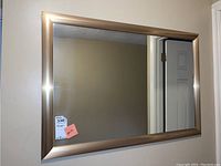 Front view of rectangular wall mirror with metallic laminate-like frame showing overall condition and size.