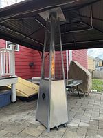 Full view of pyramid stainless steel patio heater outdoors under gazebo