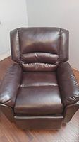Front view of deep brown bonded leather kids size recliner showing cushioned seat, backrest, and armrests.