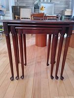 Front view of three nested mahogany tables showing graduated leg heights