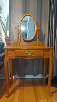 Front view of wooden vanity desk with oval mirror and single drawer