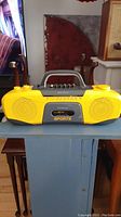 Front view of vintage yellow and gray Sony Sports boombox with handle and speakers visible.