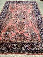 Overhead view of entire rug showing pink field, central medallion and navy border